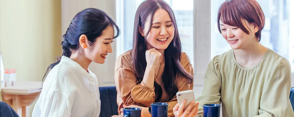 飲食店で女性陣がスマホを見ている様子の画像