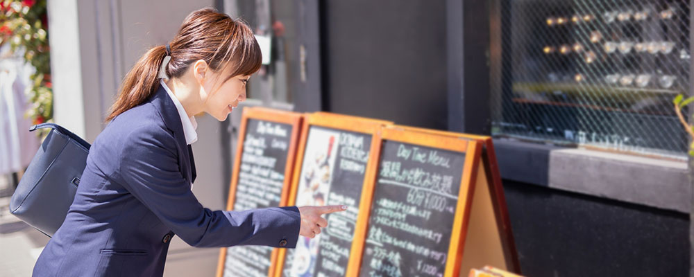 看板に指をさすスーツの女性の画像