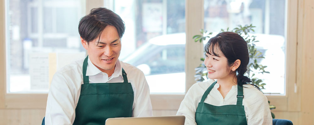 二人の飲食店スタッフがパソコンを見ている画像