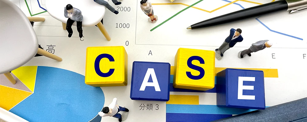 グラフ用紙の上に並べられた「CASE」の文字ブロックとビジネスマンのミニチュア