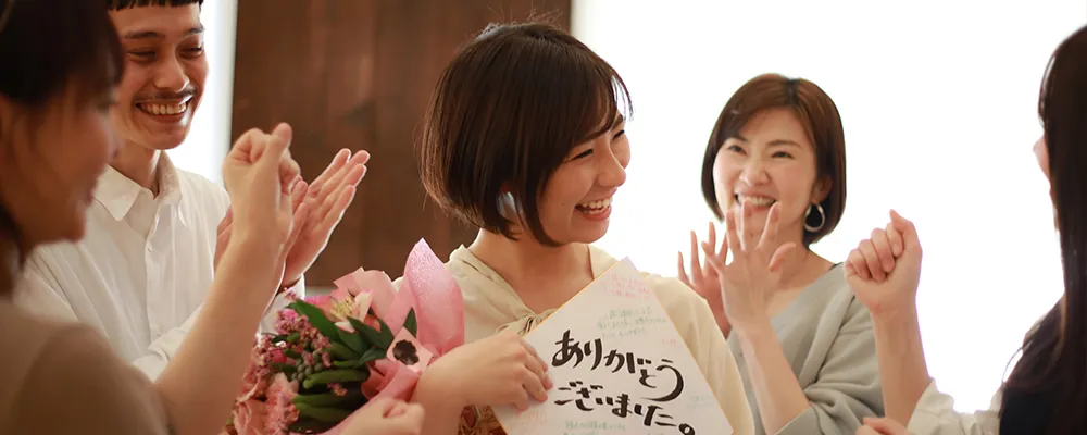 花束と寄せ書きを持って喜ぶ女性の画像