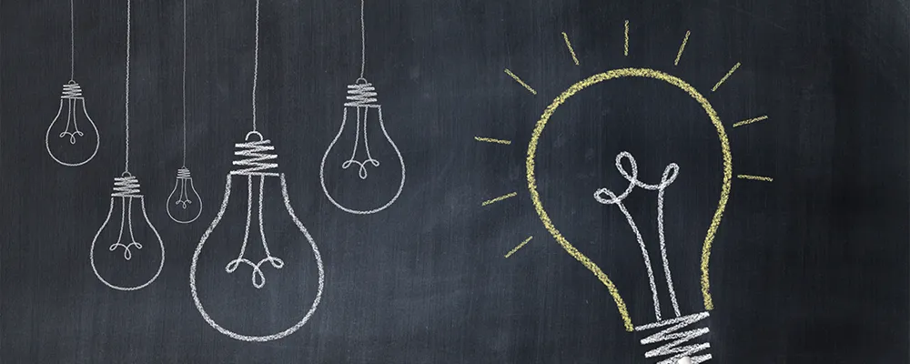 黒板に描かれたひらめきを意味する光る電球の画像