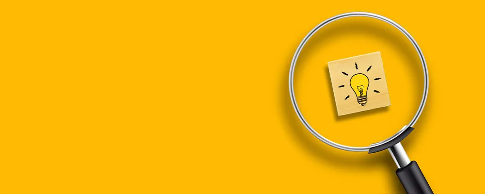 虫眼鏡で覗いた光る電球のイラストの画像