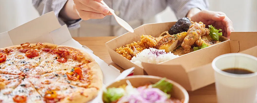 テーブルに並んだ様々なテイクアウト料理の画像