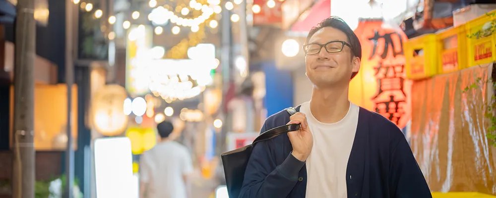 夜の街で晴れやかな表情を浮かべる男性の画像