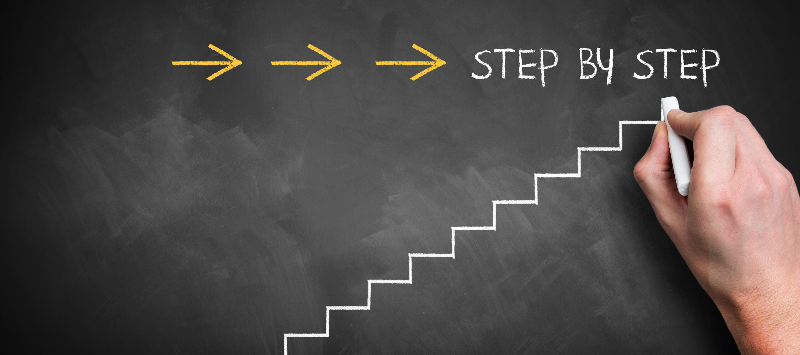 「STEP BY STEP」と書かれた黒板の画像