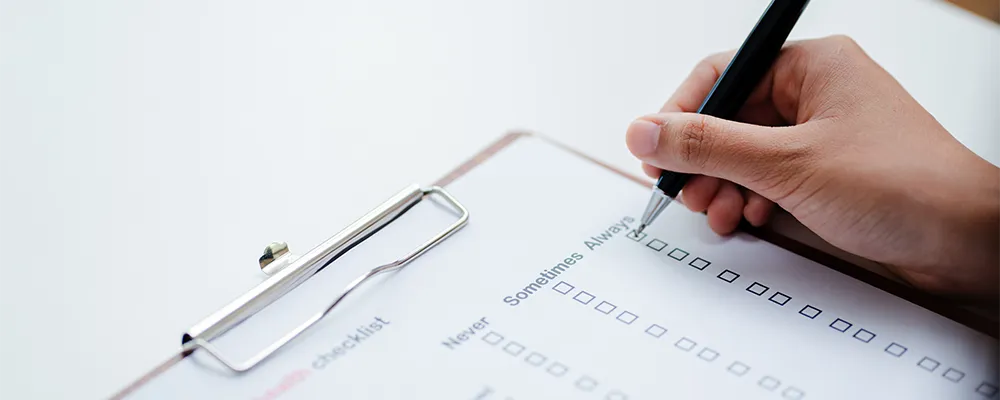 チェックリストに記入する手の画像